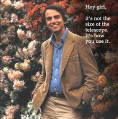 a man is standing in front of some flowers and smiling at the camera with his hands in his pockets