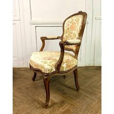 an old fashioned chair sitting on top of a hard wood floor next to a white wall