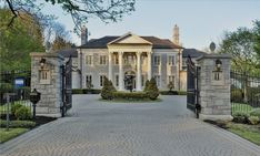 an entrance to a large home with stone pillars and gates leading into the front yard