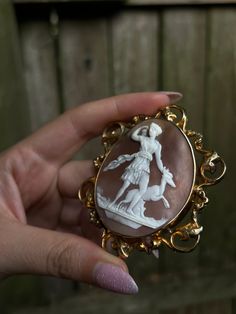 Romantic and whimsical, this rare 19th century brooch is a museum-quality adornment! Crafted circa 1850, this brooch is set in 12 carat gold and features a stunning Baroque frame. Also beautiful is the soft, rosey peach-hued cameo shell, upon which we see the delicate visage of the Greek Goddess Diana, and the Theban hero Actaeon in the form of a stag. As the myth goes, Diana was bathing at a hidden spring when Actaeon stumbled upon her naked figure. Outraged at the invasion of privacy, the embarrassed Diana punished Actaeon by destroying his power of speech, and turning him into a shaggy-haired stag with large antlers. And indeed, in this cameo, we see the figure of Artemis standing defiantly upright, one hand reaching for her quiver of arrows, and the other placed sternly upon the top of Elegant Yellow Gold Baroque Brooches, Yellow Gold Baroque Brooch For Formal Occasions, Antique Yellow Gold Brooches With Intricate Design, Elegant Baroque Brooches For Formal Occasions, Formal Yellow Gold Baroque Brooches, Vintage Yellow Gold Baroque Brooch, Elegant Cameo Brooch For Formal Wear, Elegant Formal Brooch With Intaglio Detail, Elegant Intaglio Brooch For Formal Occasions