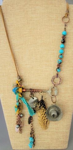 "This is for sure a One Of A Kind necklace. Designed with a genuine skeleton key. Included is vintage Sari silk, ant. copper chain with charms and feathers. A vintage (over 50 years old) cowboy hat (likely made of pewter) that started it's life as a button cover. The necklace has genuine blue semi precious stones (Wagnerite chips and 8mm  reconst. Siderolite with  with copper. Necklace can adjust from a choker length to a  a Princess length, depending on body type. I can easily fit it over my head and adjust from there. Micro-suede gives this a more casual appeal.  The \"Story\" charm represents what everyone has...a story. The vintage pieces add to that. Perhaps the hat and feathers speak to a person who was raised on a farm or horse farm or their family comes from a farm background. It c Bohemian Bronze Jewelry For Vintage Collection, Bohemian Style Bronze Jewelry For Vintage Collection, Bohemian Charm Necklaces For Vintage Collection, Bohemian Bronze Jewelry With Vintage Charm, Bronze Bohemian Jewelry With Vintage Charm, Bohemian Jewelry With Keys As Gift, Chain With Charms, Sari Silk Jewelry, Old Cowboy