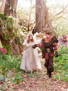 two people dressed up in costumes walking through the woods