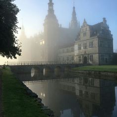 a foggy castle with a bridge over the water