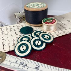 sewing supplies including thread and spools sit on a table next to a measuring tape