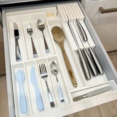 an open drawer with utensils and spoons in it