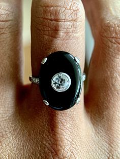 An exceptionally scintillating diamond and onyx cocktail ring. 18K white gold cocktail ring featuring an oval onyx cabochon, approx. 0.40 carats of old European cut diamond and rose cut diamonds at shank. Hallmark: No Hallmark, Tested for 18K Purity Metal Type: 18K White Gold Total Item Weight (g): 5.0 Clarity Grade: SI1 Gemstone: Diamond Fluorescence: Faint Stone Shape: Old European Cut Color Grade: H-I Carat Weight: 0.4 Stone Dimensions (mm): Avg. Diameter 1.05 Clarity Grade: Slightly Included Formal Oval Cabochon Diamond Ring, Art Deco Diamond Rings With Cabochon, Art Deco Diamond Cabochon Rings, Classic Diamond Ring With Cabochon Cut, Classic Diamond Cabochon Ring, Oval Cabochon Diamond Ring, Luxury Oval Black Enamel Rings, Oval Cabochon Platinum Rings, Timeless Diamond Rings With Cabochon