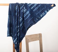 a chair with a blue and white blanket draped over it's back next to a wooden chair