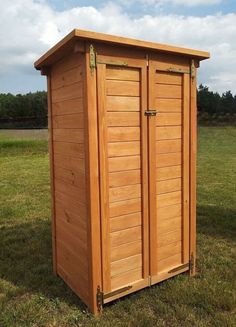 a large wooden storage shed sitting on top of a grass covered field