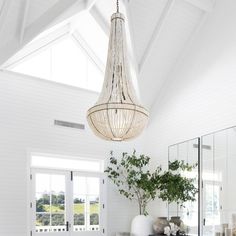 a white room with a chandelier hanging from the ceiling and furniture on the floor