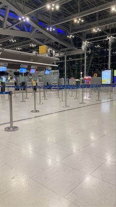 an empty airport terminal with blue and white check - in counters on either side of the gate