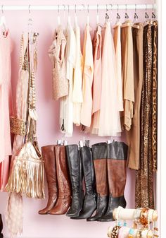 a closet filled with lots of different types of clothes and boots hanging from hooks on the wall