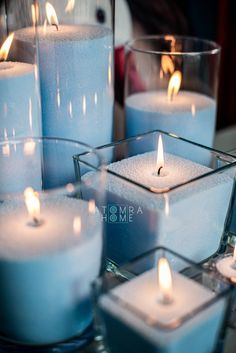 several lit candles in glass containers on a table