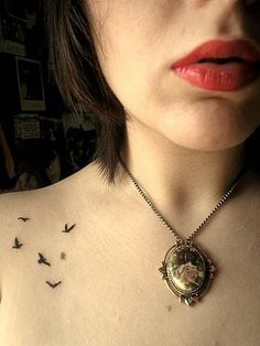 a woman with tattoos on her chest and birds flying around