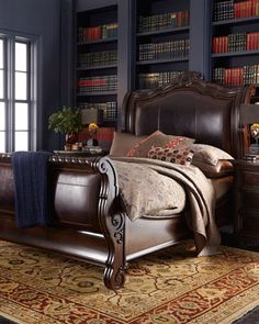 a large bed sitting in a bedroom next to a book shelf filled with books and pillows