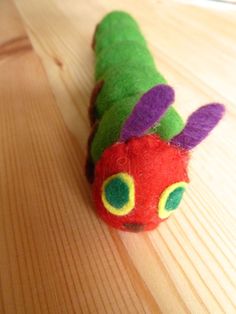 a very cute toy caterpillar sitting on top of a wooden table