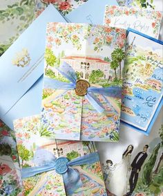 wedding cards and envelopes are laid out on a bed sheet with flowers, palm trees and watercolor paintings