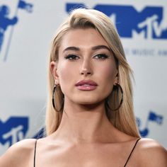 a woman with long blonde hair and large hoop earrings on her head, posing for the camera