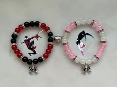 two bracelets with charms on them sitting next to each other