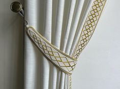 white curtains with gold trim hanging on the wall