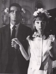 a man and woman standing next to each other in front of a mirror with flowers on their head