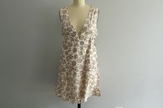 Get ready for spring and summer with this adorable floral print halter mini dress! The A-line silhouette and ruffled edge hem create a flowy and feminine look, perfect for a day at the beach or brunch with friends. The dress is fully lined and features a beige and white color scheme, making it the perfect vacation dress. You'll love the way you feel in this resort-inspired piece Available in Beige Taupe from Size Small to Large. Small (2/4), Medium (6/8), Large (10) Small  - Waist (without stret Vintage Sleeveless Beach Mini Dress, Vintage Mini Dress For Beach, Vintage Cotton Mini Dress For Vacation, Vintage Sleeveless Mini Dress For Brunch, Vintage White Mini Dress For Vacation, White Vintage Mini Dress For Vacation, Beach Brunch, Brunch Dress, Cozy Tops