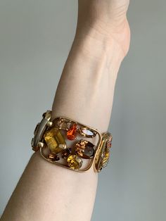 "Vintage 1940's statement signed Napier bracelet. Gold tone bracelet with amber, brown, and bright orange rhinestone crystals. Rhinestones are oval, circle, baguette, emerald, and tear drop cut. Bracelet in excellent condition with minor wear due to age. High quality and high shine rhinestones. Measurements Length: 6-3/4\" / Width: 1-1/2\" / Unless otherwise stated all vintage items are used and may have minor to moderate wear or discoloration considering the age of the item. Most items have bee Luxury Jeweled Metal Bracelets, Brown Rectangular Metal Jewelry, Rectangular Brown Metal Jewelry, Vintage Jeweled Gold Cuff Bracelet, Vintage Amber Rectangular Jewelry, Brown Bangle Jewelry For Formal Occasions, Brown Bangle For Formal Occasions, Vintage Jeweled Cuff Bracelet For Formal Occasions, Vintage Amber Jewelry For Party