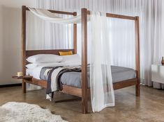 a bed with white drapes and pillows on it