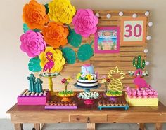 a wooden table topped with lots of desserts and flowers next to a sign that says 30