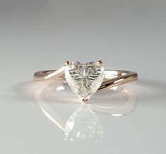 a heart shaped diamond ring on a reflective surface