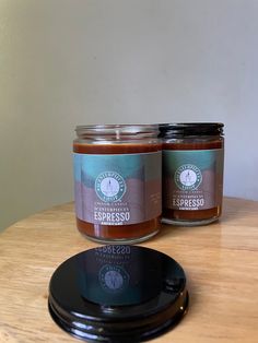 two jars of preserves sitting on top of a wooden table