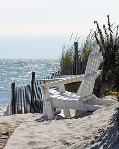 a white beach chair sitting on top of a sandy beach next to the ocean with an inspirational quote above it