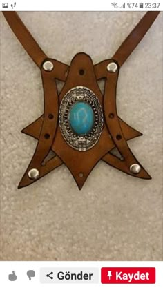 a necklace with a turquoise stone in the center on a brown leather belt that is attached to a white carpet