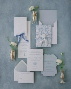 the wedding stationery is laid out on top of each other with flowers in vases