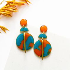 These colourful statement earrings are made from hand casted eco friendly resin coloured with orange and turquoise opaque pigment.  All of the components are brass apart from the ear posts and backs which are nickel free, hypoallergenic stainless steel, so they're perfect for sensitive skin.  Measuring approximately 3cm width x 6cm length, you don't need to worry about them being heavy...as resin is lightweight they're super comfortable.  ❤️ Your jewellery will arrive on a presentation card and wrapped in tissue. If your sending as a gift and want me to include a note from you, on plain card, just leave a message at checkout. If you'd prefer your message on a cute birthday card they're available for £2, here's the link - https://www.etsy.com/uk/listing/1128179895/birthday-card-available-wh Artsy Orange Drop Earrings, Vibrant Orange Drop Earrings, Orange Dangle Resin Earrings, Orange Resin Dangle Earrings, Handmade Retro Orange Earrings, Retro Handmade Orange Earrings, Modern Orange Drop Earrings, Bold Orange Drop Earrings, Orange Resin Earrings