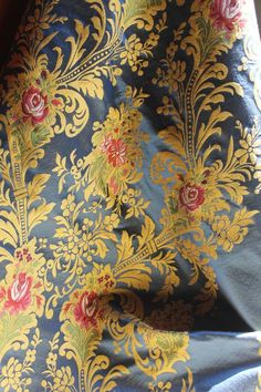 a blue and yellow fabric with red flowers on the side, in close up view