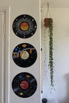 three vinyl records are hanging on the wall next to a plant and potted plant