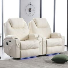 two white recliners sitting next to each other in front of a wall clock