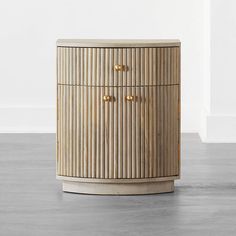 a wooden cabinet sitting on top of a floor next to a white wall in an empty room