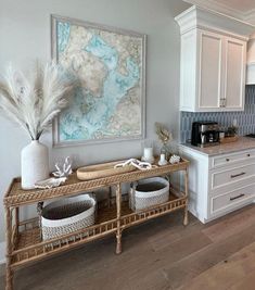 a kitchen with white cabinets and wooden flooring next to a painting on the wall