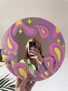 a woman taking a selfie in front of a mirror with her cell phone and some plants