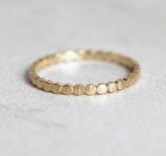 a gold ring sitting on top of a white surface with small dots in the middle