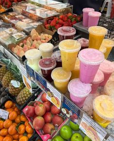 there are many fruits and juices on display at this market stall, including oranges, strawberries, apples, lemonade, and smoothies