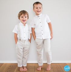 two young boys standing next to each other in front of a white wall and wooden floor