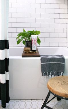 a bathroom with a bathtub, stool and potted plant on the shelf next to it