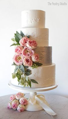 a wedding cake with pink flowers and greenery on top