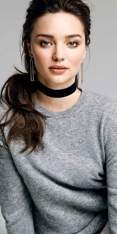 a woman wearing a black choker and grey sweater with her hair in a pony tail