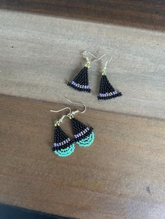 two pairs of beaded earrings sitting on top of a wooden table