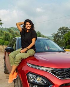 a woman sitting on the hood of a red car