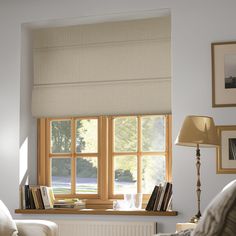 a living room with a couch, chair and window covered in roman blind shades on the windowsill