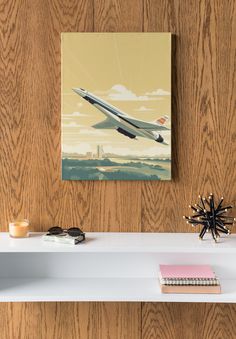 an airplane is flying in the sky on a wood paneled wall above a white shelf